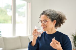 Photo of woman in her 50s taking vitamin supplements
